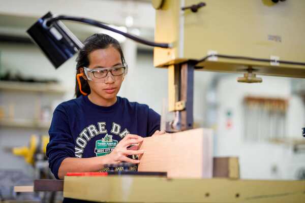 Student using tools in wood shop furniture studio