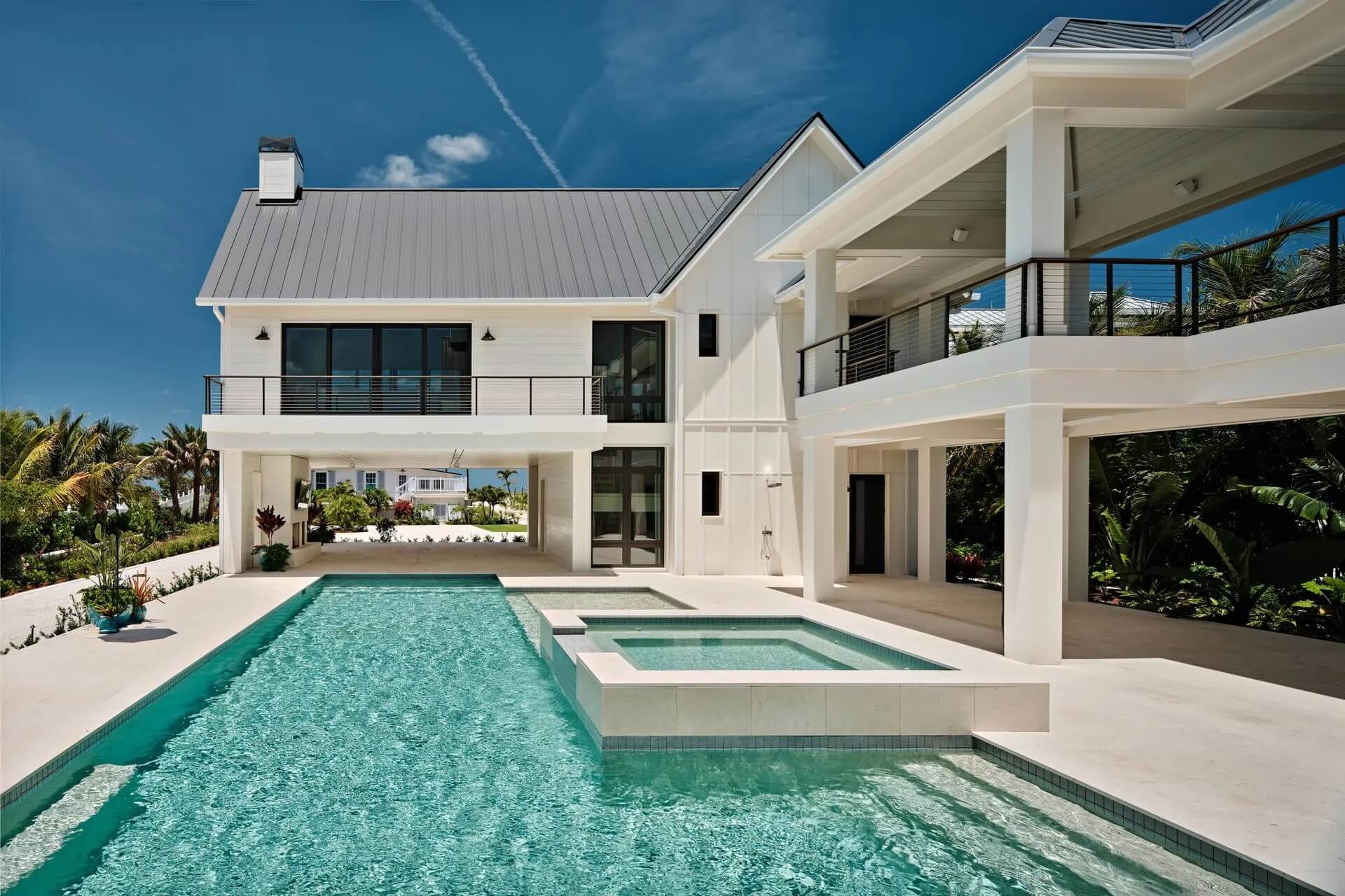Bright white multi-story private residence with a gray roof, balconies, turquoise pool, in Captiva Island, Florida.